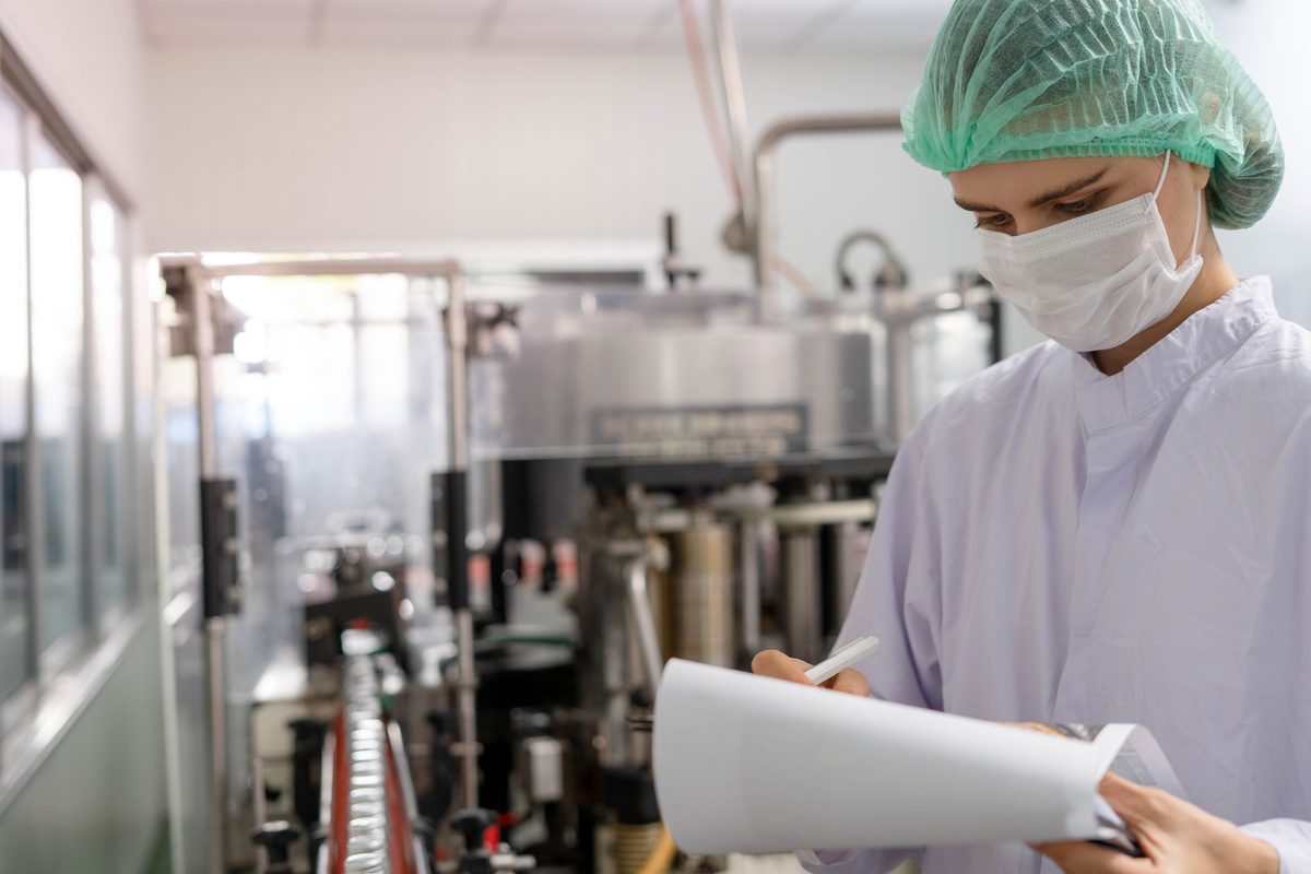 An inspector with a clipboard checking orders on a production line